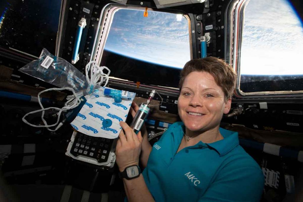 Flight Engineer Anne McClain in the cupola holding biomedical gear for MARROW